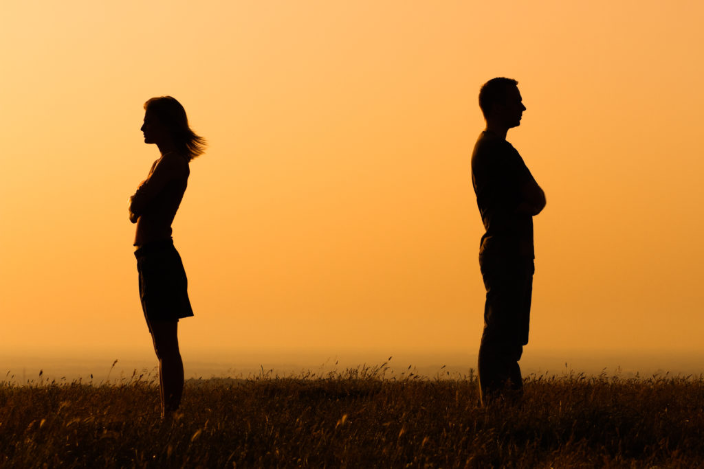 The Benefits Of Hiring A Divorce Lawyer - silhouettes of man and woman on sunset background yellow